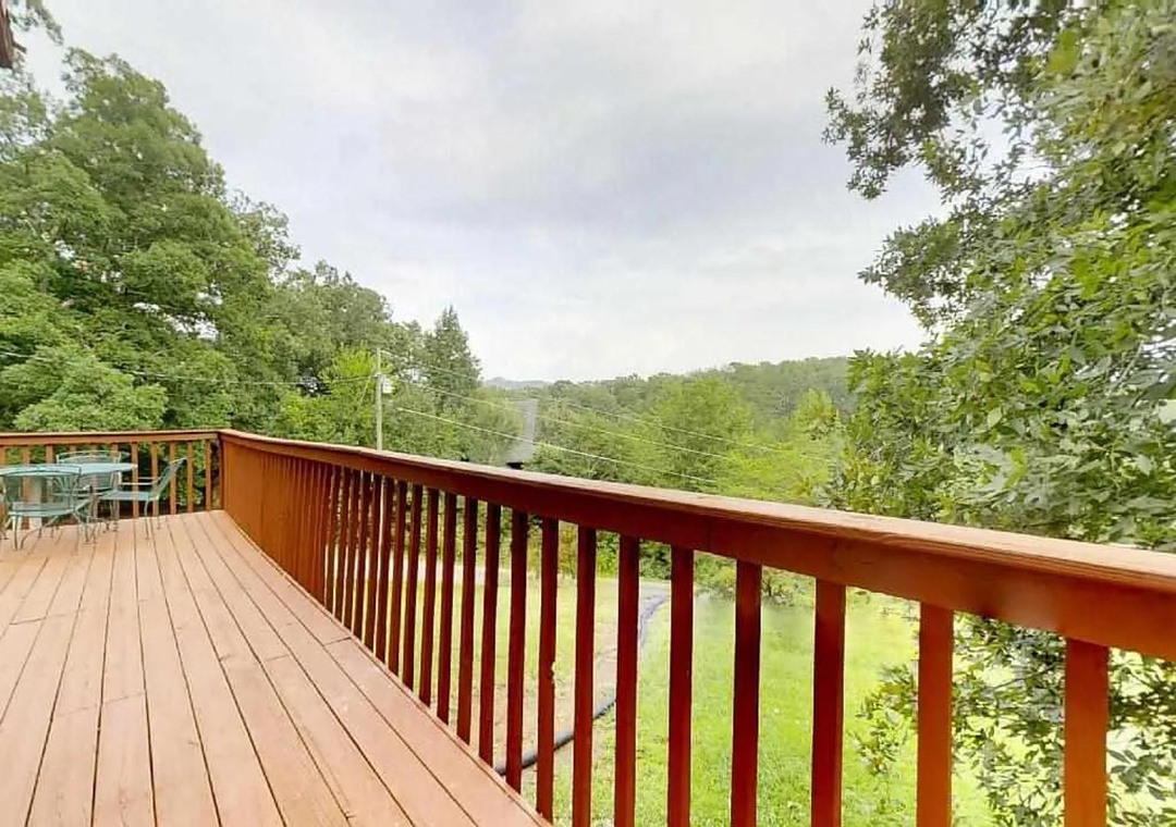 Expansive deck overlooking lush rolling hills and verdant landscape, perfect for morning coffee or evening relaxation in nature's embrace.