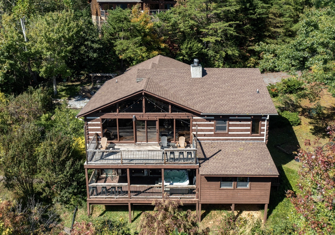 An inviting log cabin nestled in a lush forest setting, offering secluded mountain charm with spacious multi-level decks for enjoying the pristine natural surroundings.