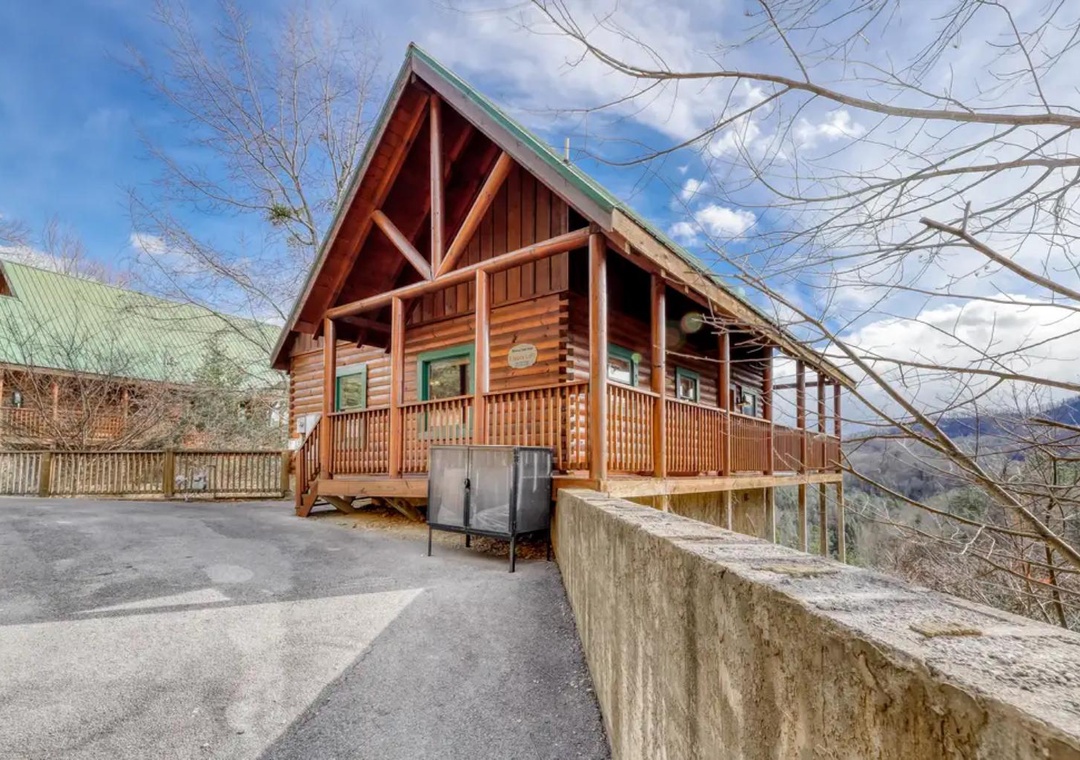 A welcoming mountain cabin featuring warm wood construction and a spacious wrap-around deck, set among the Smoky Mountain foothills with convenient parking and views of the natural landscape.