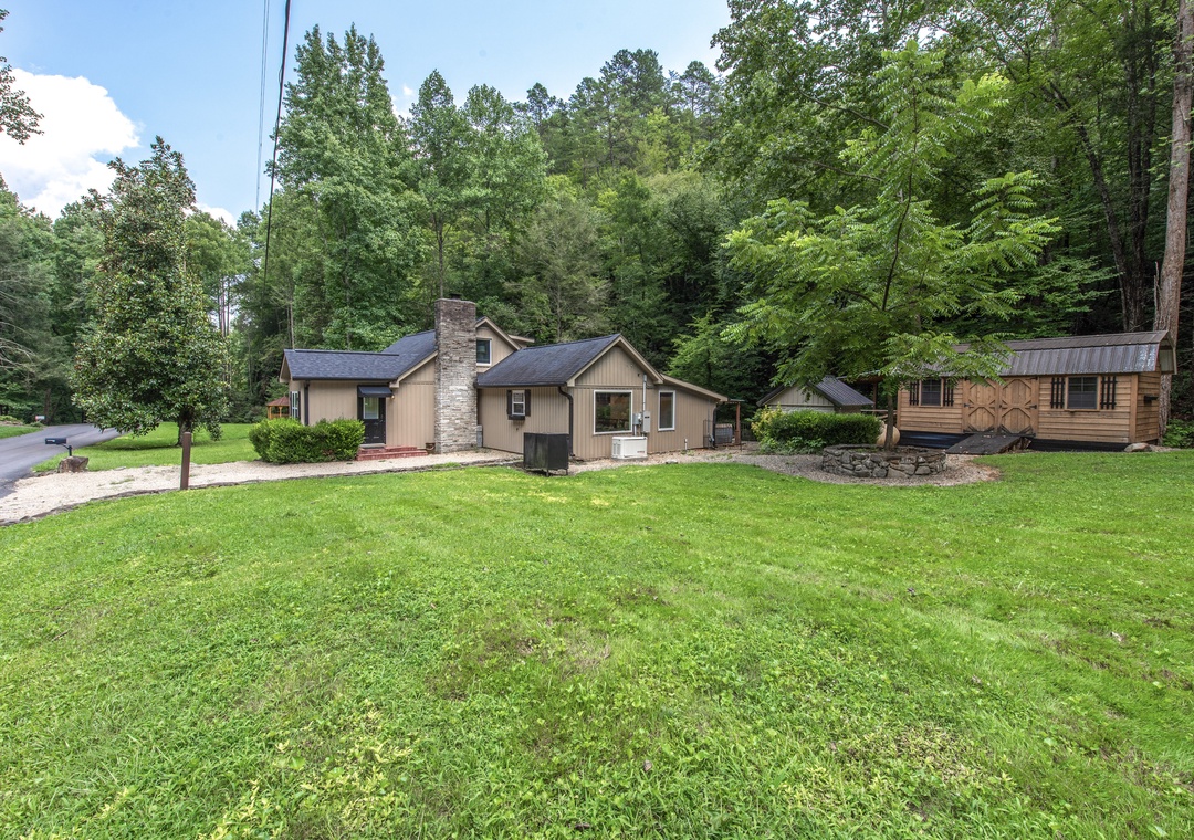This charming property is nestled in a peaceful wooded setting with plenty of lawn space for outdoor activities. The main house features a stone fireplace accent and multiple buildings offer flexible accommodations.