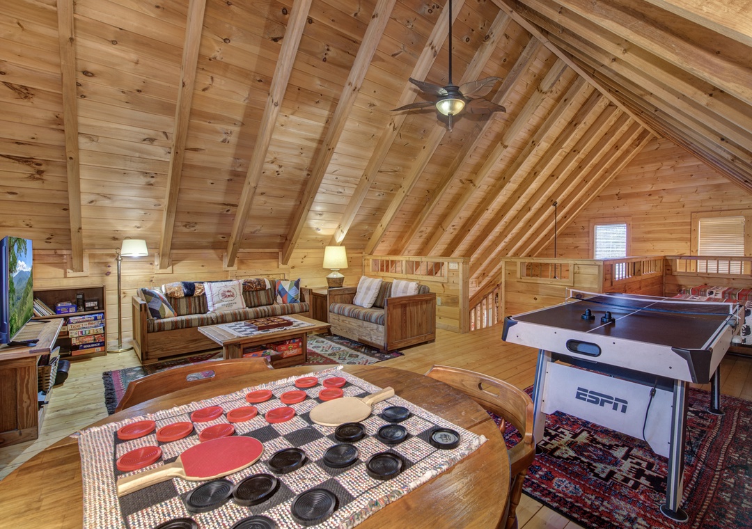 Your private game loft awaits with air hockey, checkers, and cozy seating under rustic wood beams.