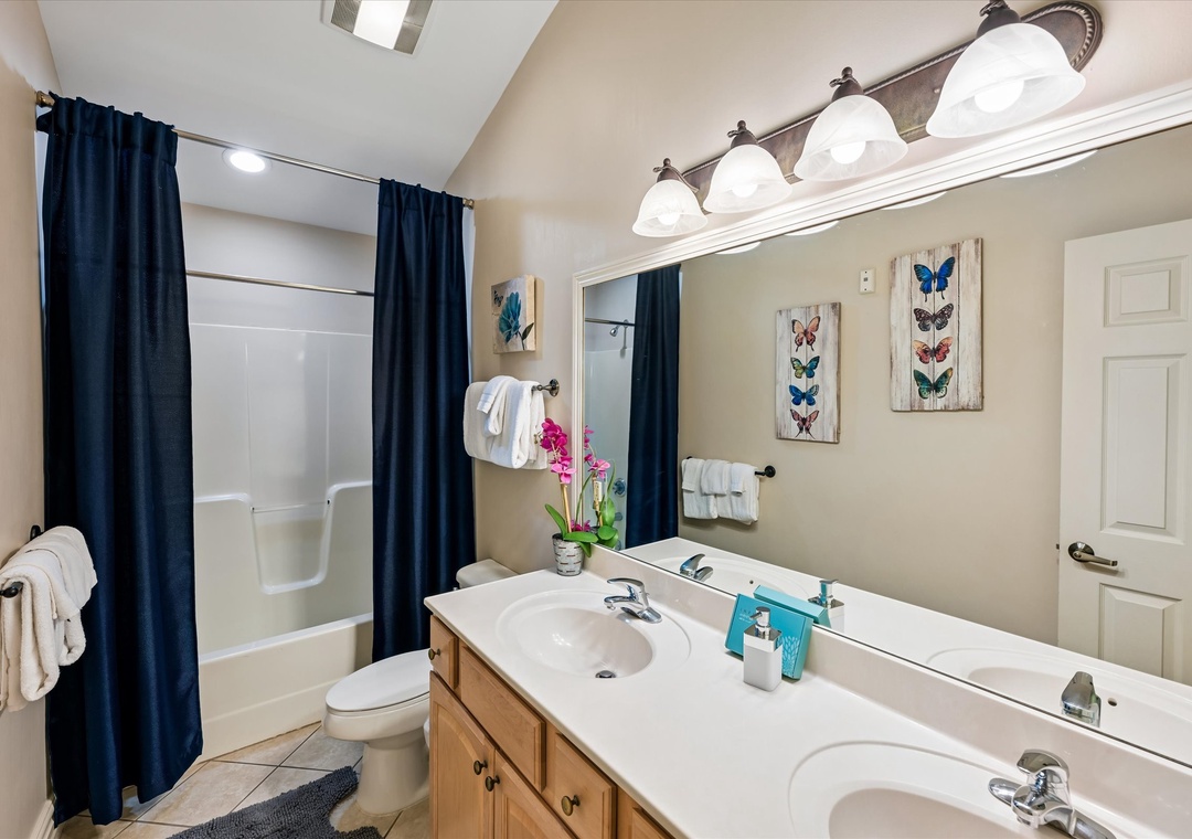 Refresh in your spacious bathroom with dual sinks, elegant butterfly art, and a relaxing tub-shower combo.