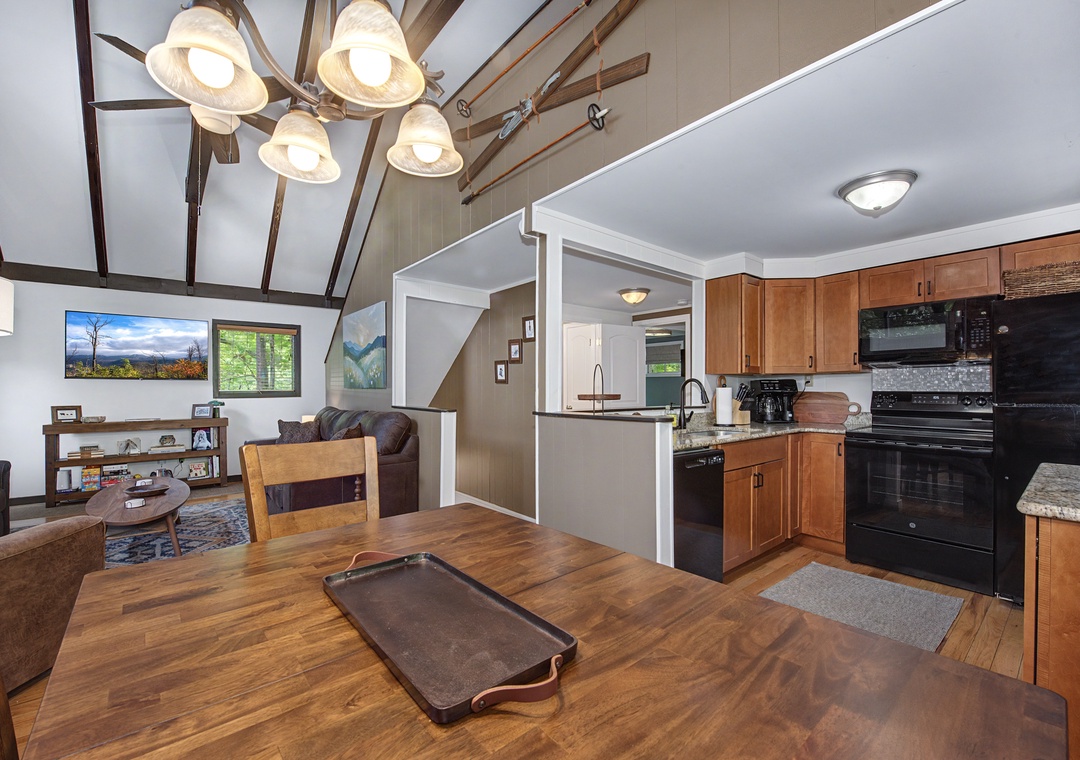 Your open-concept retreat features vaulted ceilings with exposed beams, a fully equipped kitchen with modern appliances, and a cozy living area—perfect for gathering after mountain adventures.