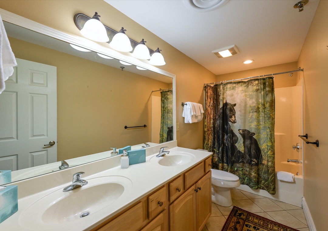 Unwind in your spacious bathroom featuring dual sinks, warm lighting, and whimsical wildlife curtains that add character to your daily routine.