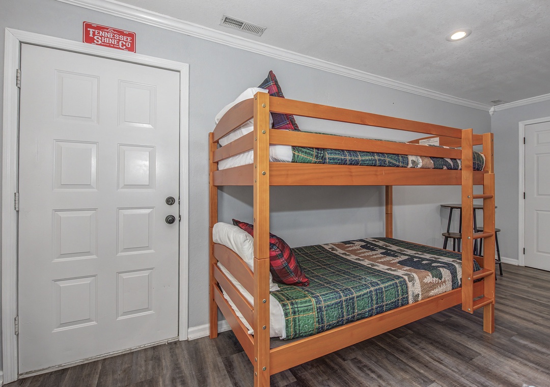 Your kids will love this cozy bunk bed setup with fun plaid bedding, perfect for family adventures in this bright, welcoming room.