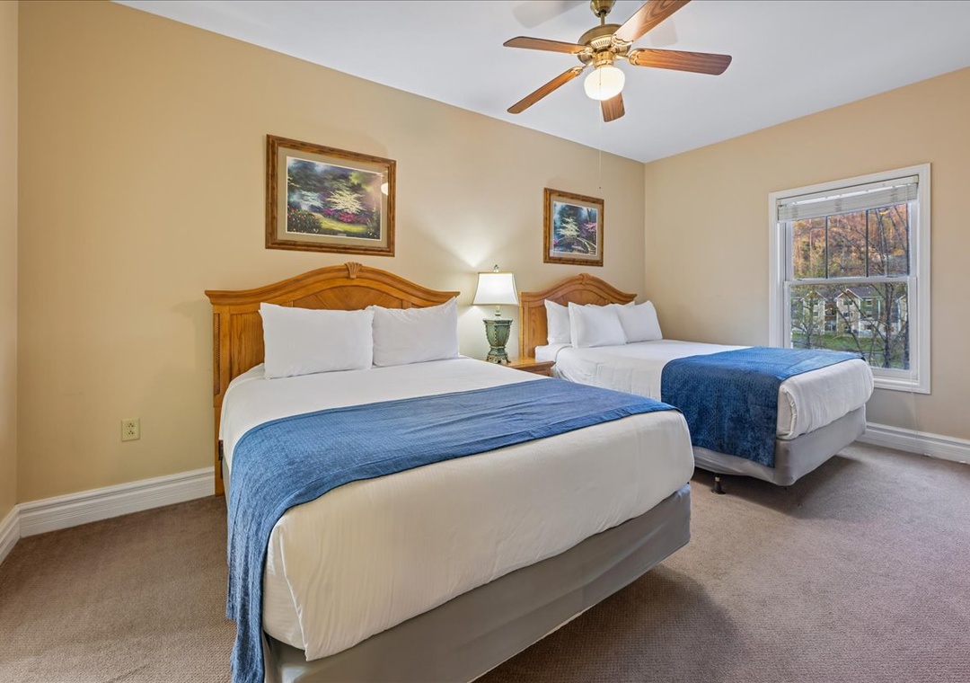 Relax in your cozy twin bedroom with plush linens, peaceful artwork, and gentle ceiling fan keeping you comfortable all night long.