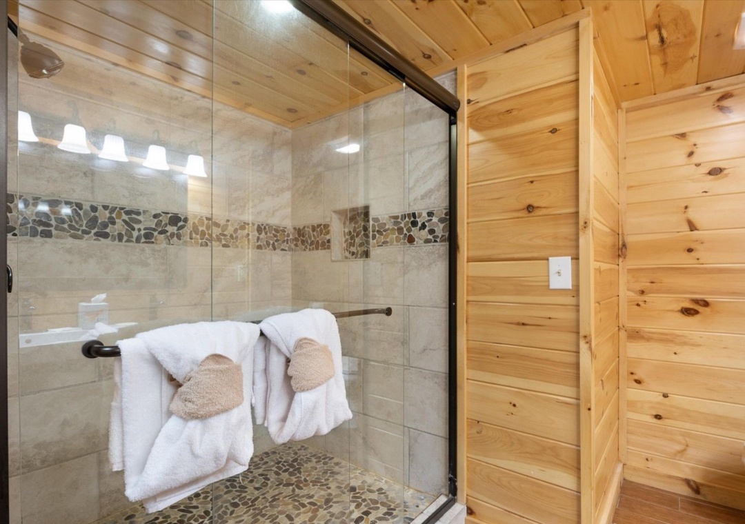 Step into your spa-like retreat with beautiful stone tile shower, cozy log walls, and plush towels waiting for your arrival.