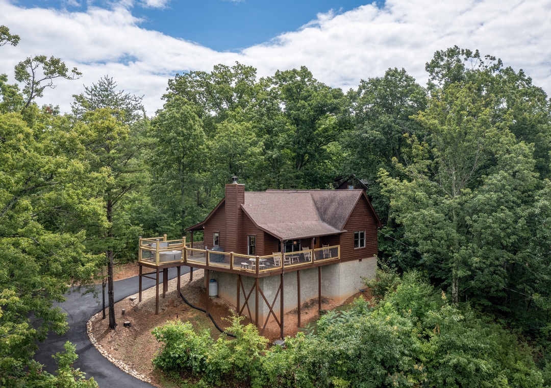 Elevated cabin nestled in lush woodland offers a private mountain escape with spacious deck and scenic forest surroundings.