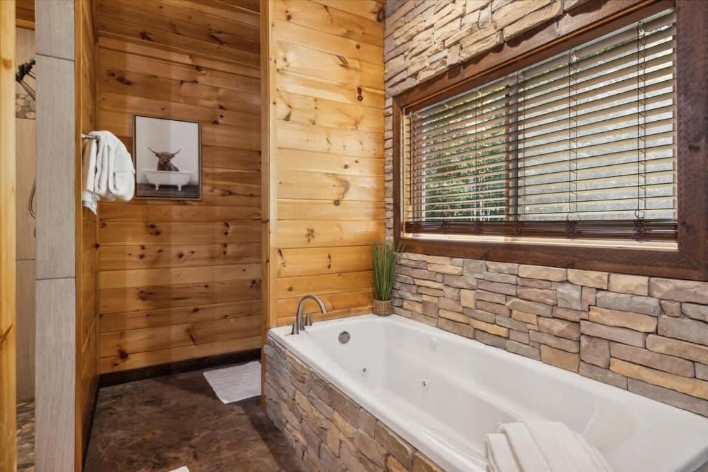 Soak away your cares in this beautiful stone-wrapped tub surrounded by warm wood and natural light—your perfect spot for unwinding after a day of adventure.