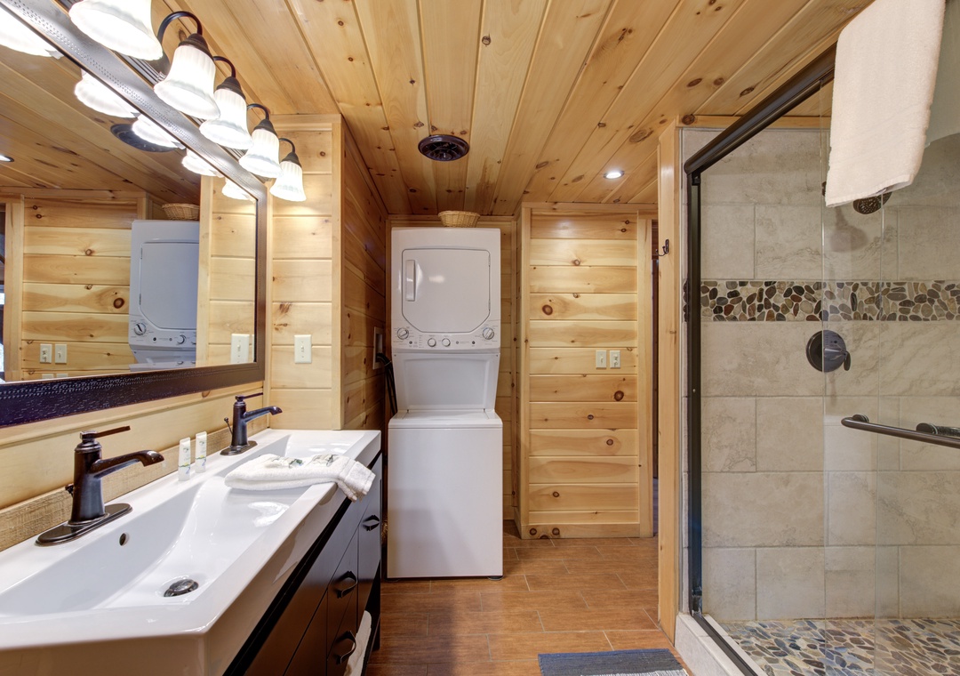 Step into your private spa retreat with dual vanities, luxurious stone shower, and charming wood-paneled warmth throughout.