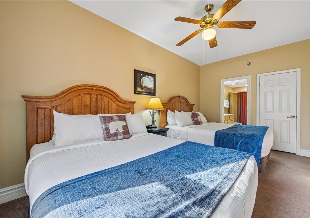 Rest easy in your cozy bedroom with two comfortable beds, warm wood headboards, and a ceiling fan for perfect temperature control.