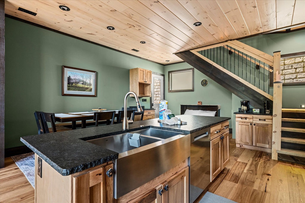 Your modern mountain retreat awaits with a sleek kitchen featuring granite counters, stainless appliances, and warm wood cabinetry. Gather around the dining table or relax in the cozy living space beneath soaring wood-planked ceilings.