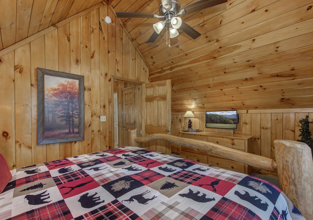 Drift off under vaulted wood ceilings in your cozy cabin bedroom, where rustic charm meets modern comfort with plaid bedding and peaceful autumn views.
