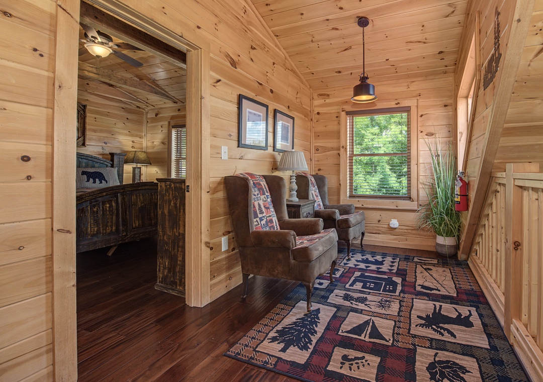 Step into your cozy cabin retreat with warm wood walls and comfy armchairs by the window. Relax with a book as natural light fills this inviting space, perfect for unwinding after exploring.