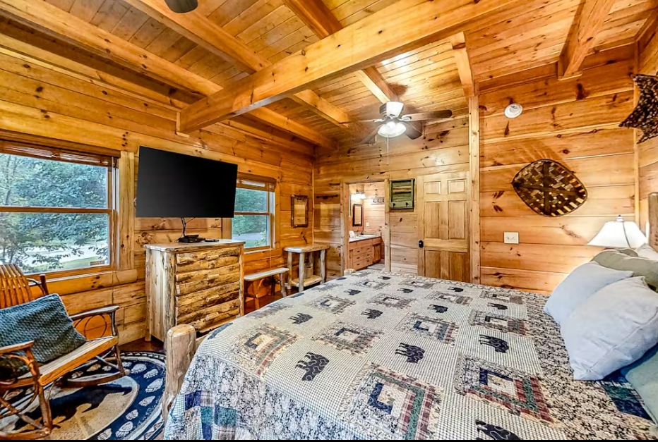 Unwind in your cozy log cabin bedroom where rustic charm meets modern comfort, complete with peaceful forest views.