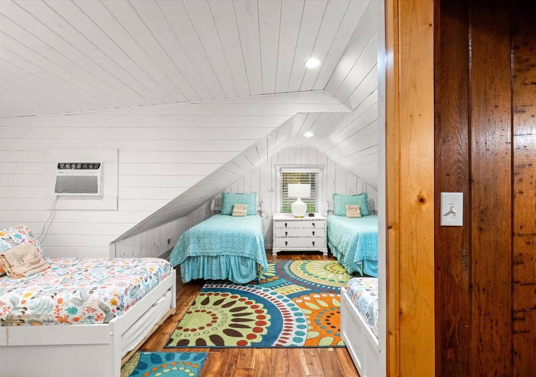Cozy attic bedroom with charming sloped ceilings, cheerful turquoise bedding, and colorful accent rugs—your family's perfect retreat after a day of adventure.