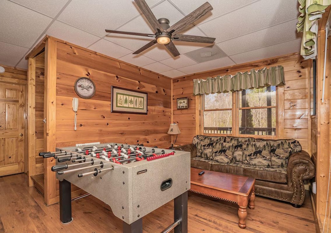 Challenge friends to foosball in your cozy cabin game room, featuring rustic wood walls and comfortable seating for post-game relaxation.
