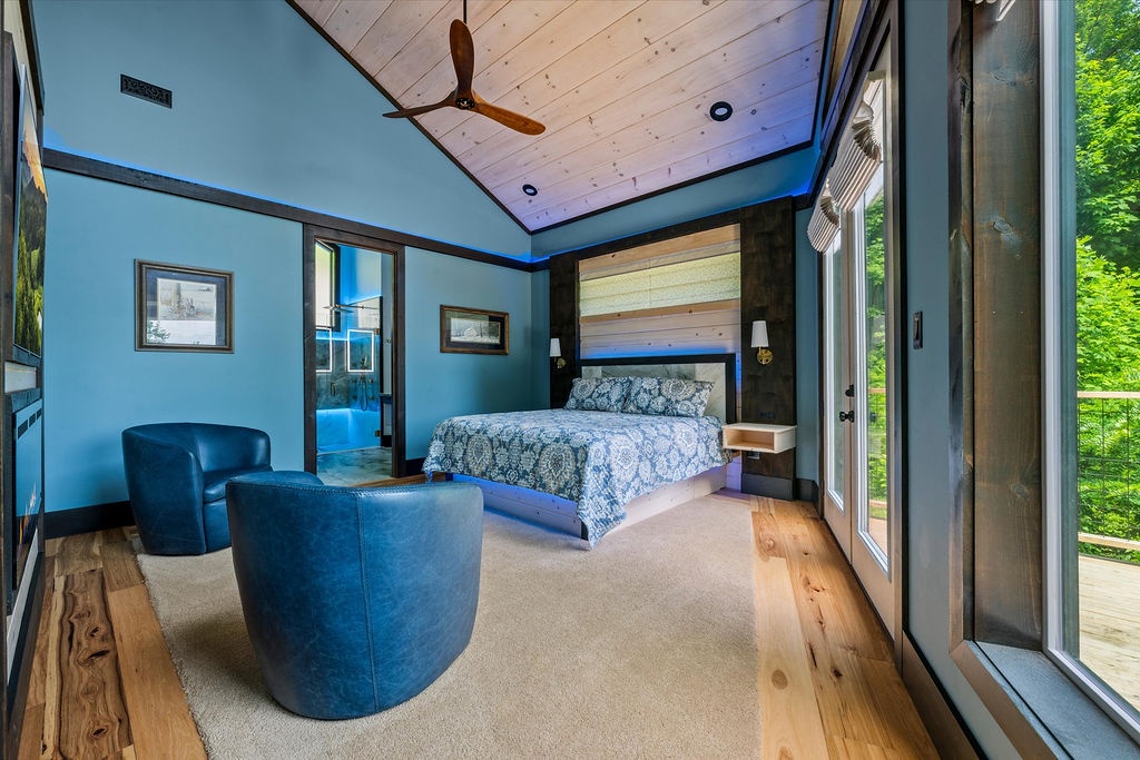 Curl up in the plush seating or sink into the inviting bed while gazing at lush green views through expansive glass doors—your peaceful retreat awaits.