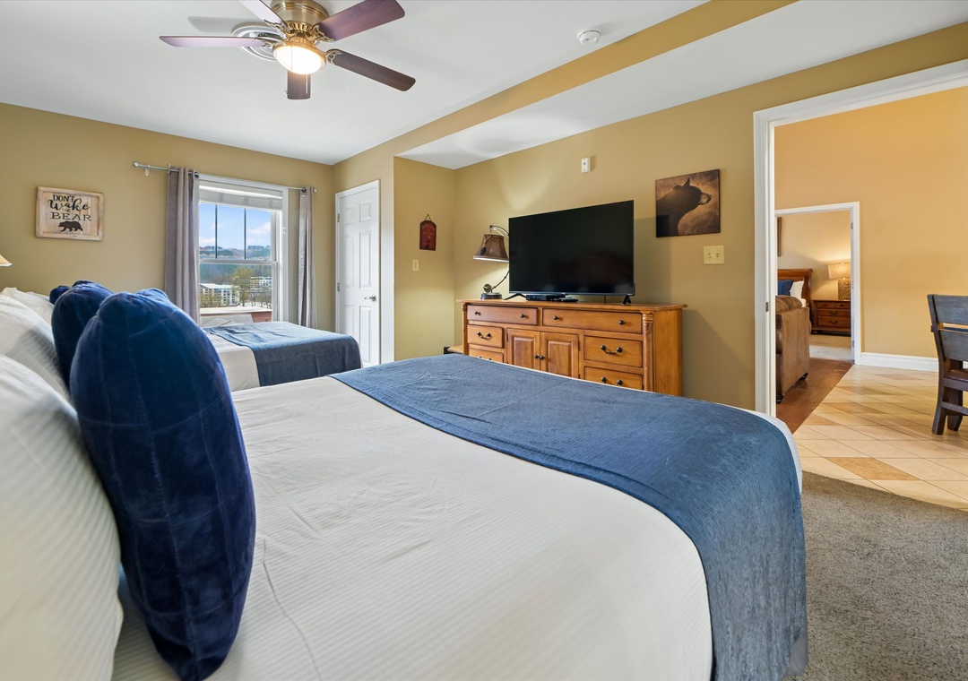 Unwind in your spacious bedroom featuring twin beds with crisp linens, a flat-screen TV, and charming decor that creates a cozy mountain retreat atmosphere.