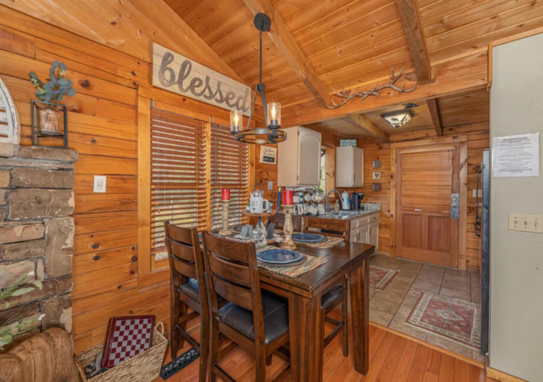 Step into your cozy cabin retreat where rustic charm meets modern comfort. Gather around the beautifully set dining table under warm wooden beams, with a stone fireplace nearby to create the perfect mountain getaway atmosphere.