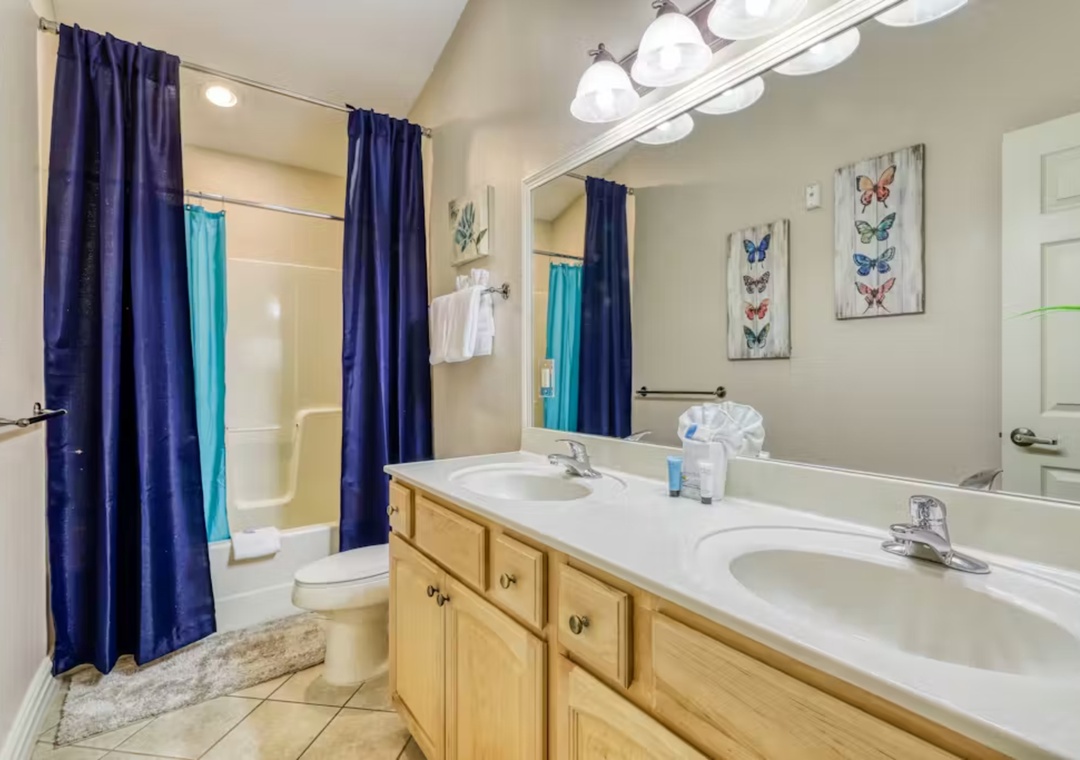 Refresh in your spacious dual-sink bathroom with charming butterfly art and bright, welcoming lighting.