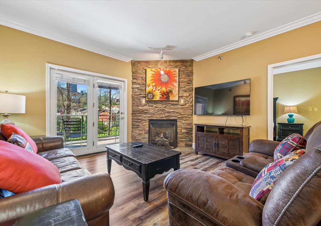 Sink into plush leather seating by your cozy stone fireplace, where warm golden walls and mountain views create the perfect retreat.