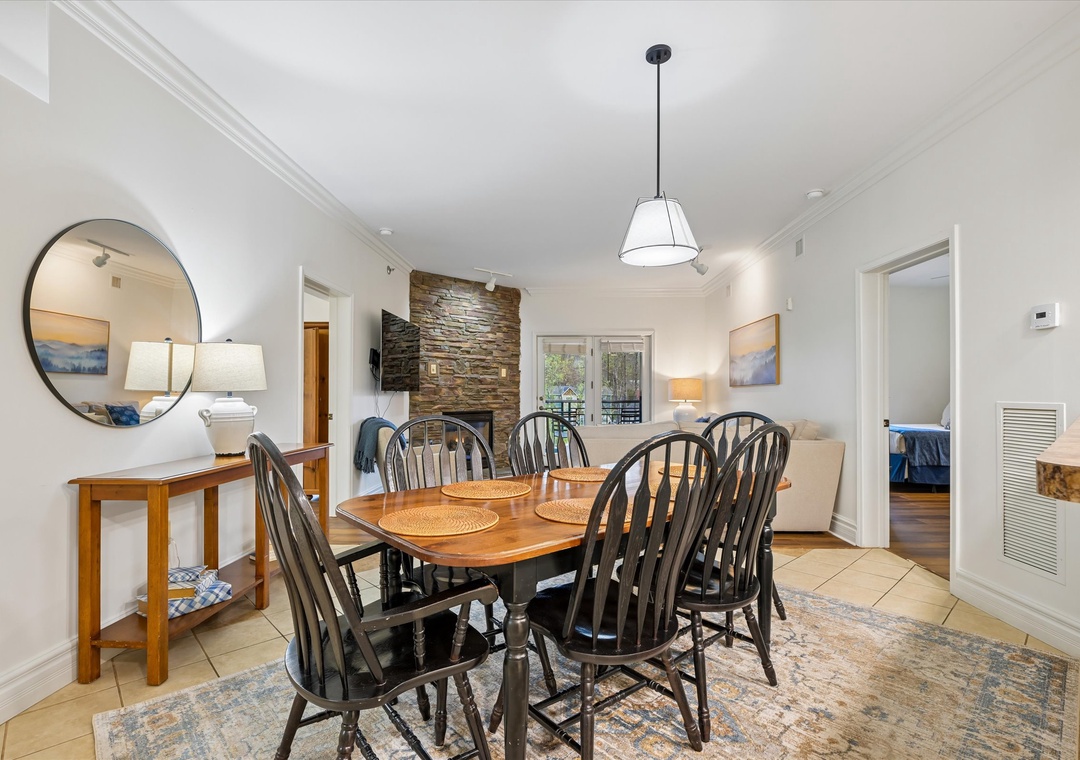 Gather around this welcoming dining table where memorable meals and conversations await, warmed by the charming stone fireplace.