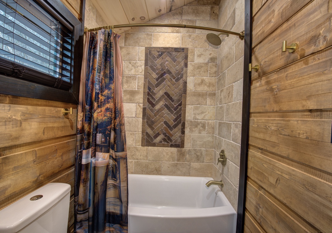 Unwind in your private stone-tiled bathroom with rustic wood paneling and rain shower.