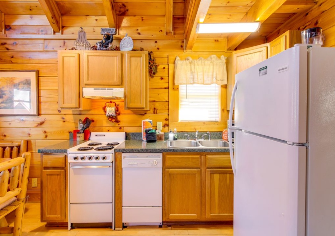 Your cozy log cabin kitchen features warm wood walls, full appliances, and rustic charm for preparing memorable meals.