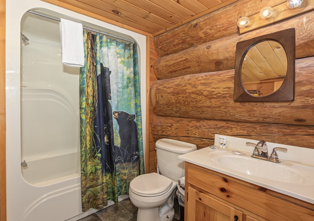 Your rustic-chic bathroom features warm wood paneling, a tub-shower combo, and a charming vanity—a cozy retreat after a day of exploring.