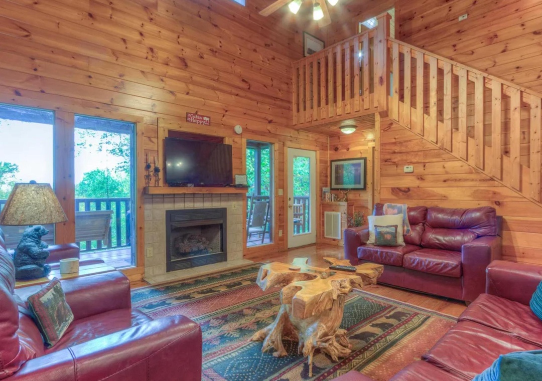 Relax in your cozy cabin living room, where rich leather seating surrounds a striking natural wood coffee table. Enjoy the warmth of the fireplace as sunlight streams through expansive windows and doors opening to your private deck.