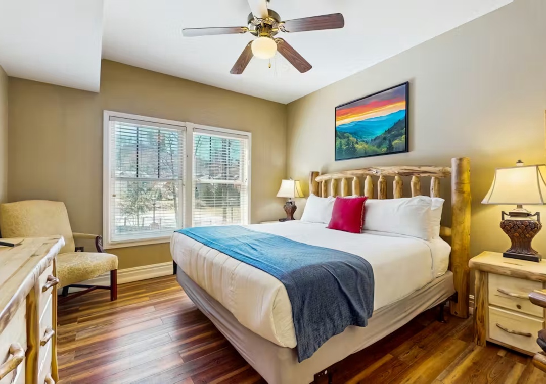 Unwind in your cozy bedroom with warm wood floors, mountain art, and a ceiling fan for perfect comfort.