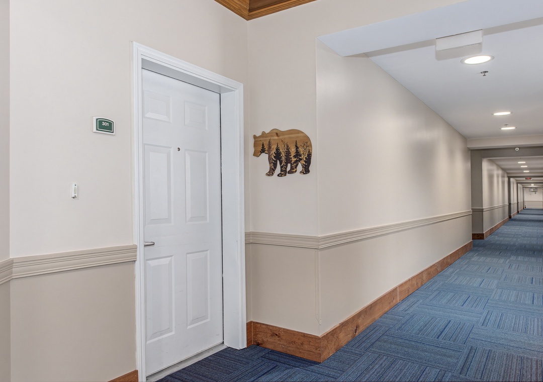 Clean, welcoming hallway with rustic bear artwork leads to your comfortable accommodations.