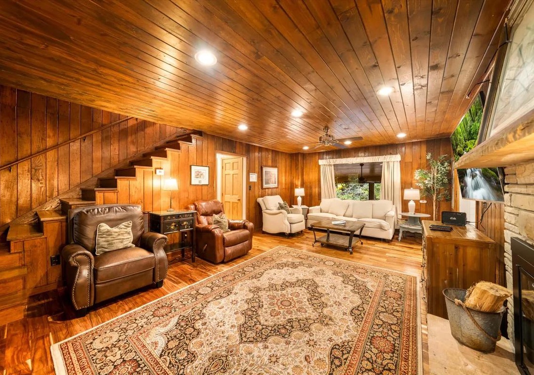 Sink into the rich warmth of this inviting living room, where natural wood surrounds you and soft lighting creates the perfect atmosphere for relaxing evenings by the fireplace.