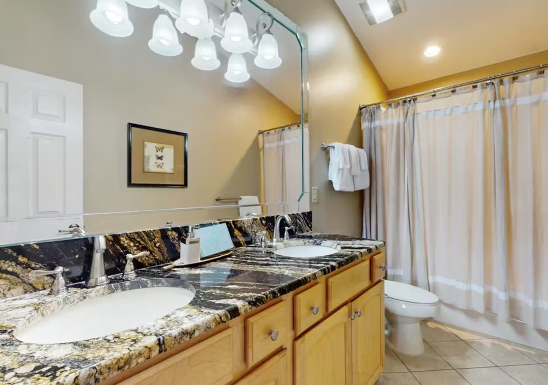 Step into your luxurious bathroom featuring elegant granite countertops, dual vanity sinks, and a relaxing shower-tub combination.