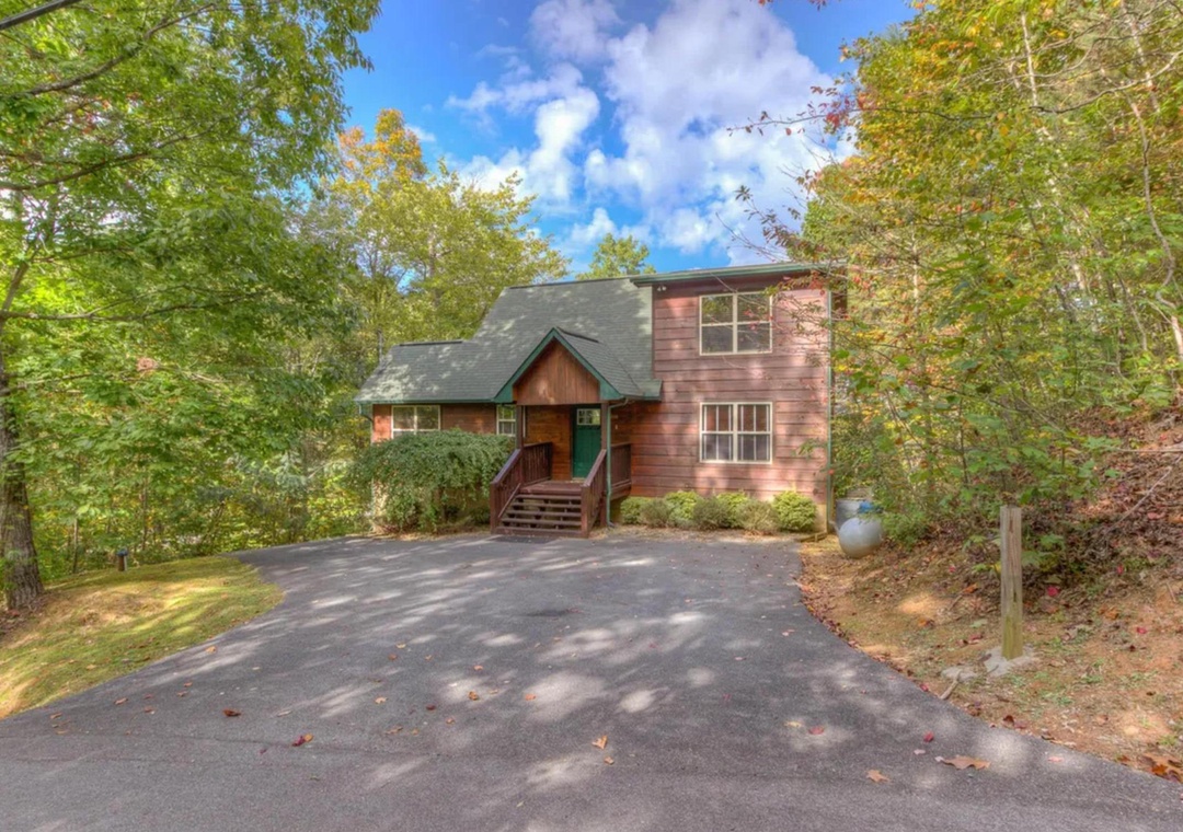 Charming mountain cabin nestled among vibrant fall foliage with spacious driveway and convenient parking. A peaceful wooded retreat with classic architecture and natural surroundings.