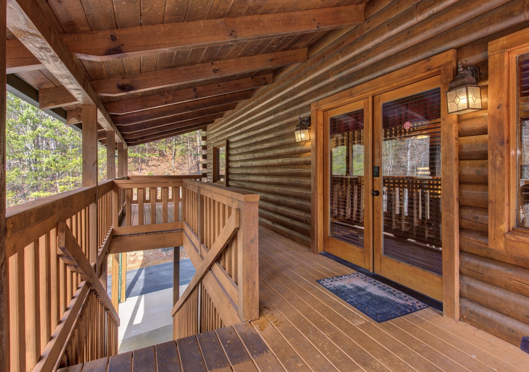 Step onto your private covered deck where rustic wood beams frame forest views and warm lantern light creates the perfect mountain retreat atmosphere.