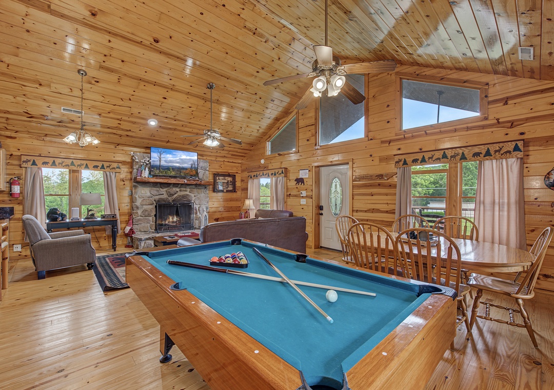 Your spacious open-plan retreat features soaring vaulted ceilings, warm wood throughout, a stone fireplace, pool table for friendly competition, and mountain views through generous windows.