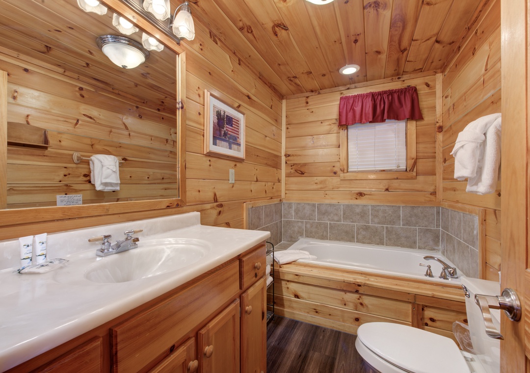 Unwind in your rustic bathroom featuring warm wood paneling and a relaxing soaking tub after mountain adventures.
