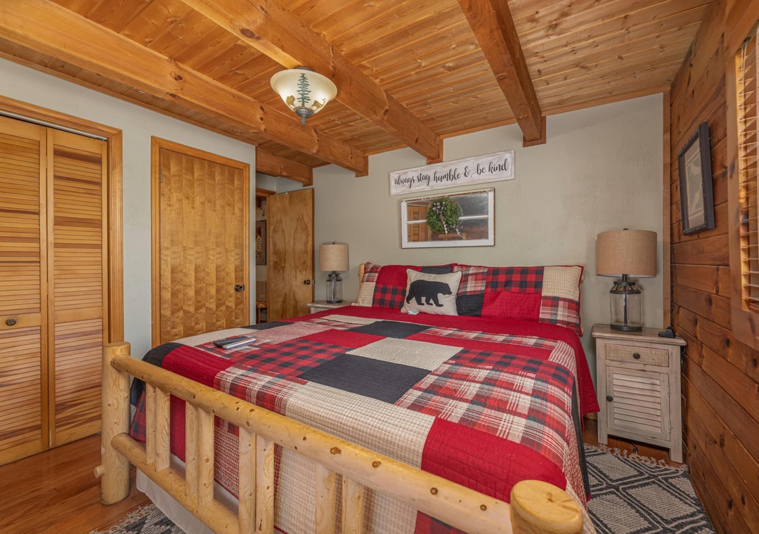 Sink into the rustic log bed under soaring wood-beam ceilings, wrapped in cozy plaid bedding that invites restful mountain nights.