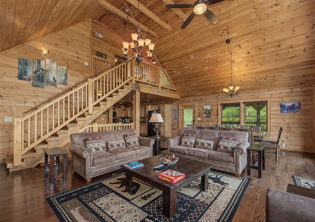 Relax in your spacious cabin's cozy living room, where vaulted wood-beam ceilings and plush seating create the perfect gathering space for unwinding after a day of adventure.