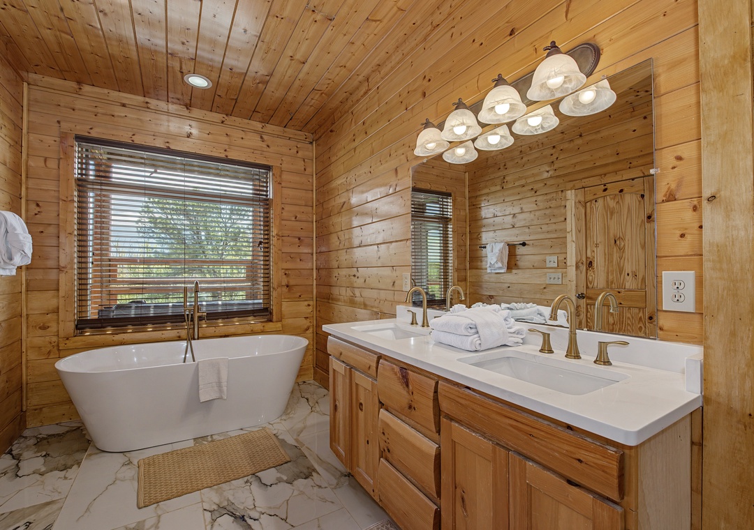 Soak in your private freestanding tub surrounded by warm wood walls and natural light streaming through blinds.