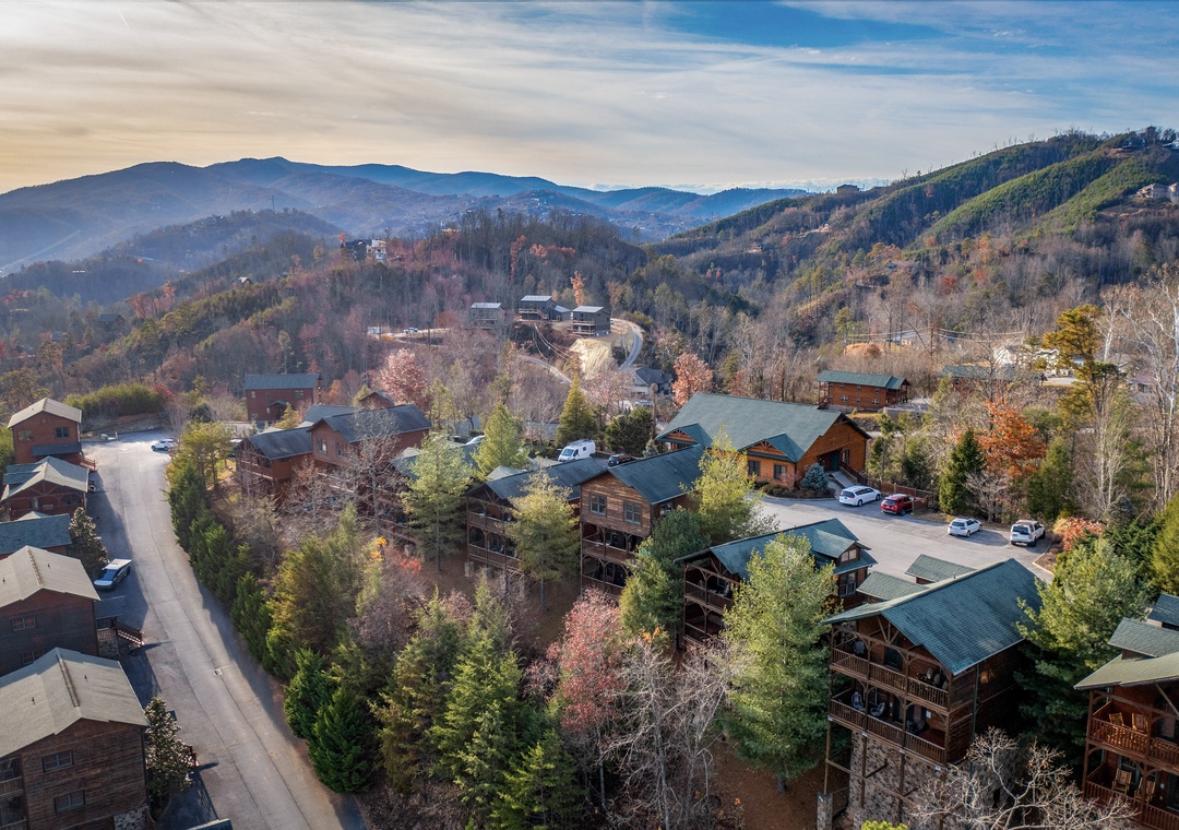 An aerial view captures the property nestled within a tranquil mountain community, surrounded by rolling peaks and scenic ridges that define this peaceful retreat.