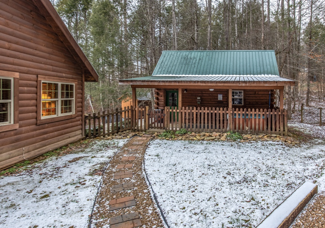 Cozy log cabins nestled among winter trees with covered porches and pathways connecting the peaceful woodland retreat.