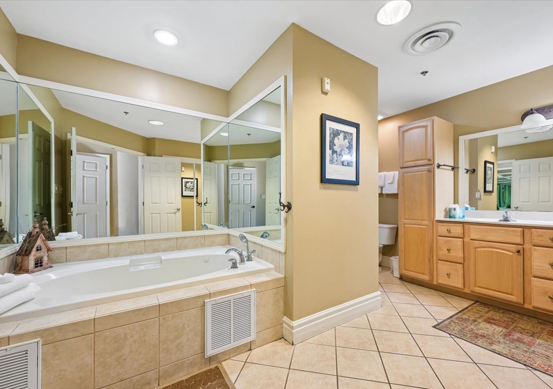 Unwind in your spa-like bathroom featuring a luxurious jetted tub, dual vanities, and elegant stone tile throughout.