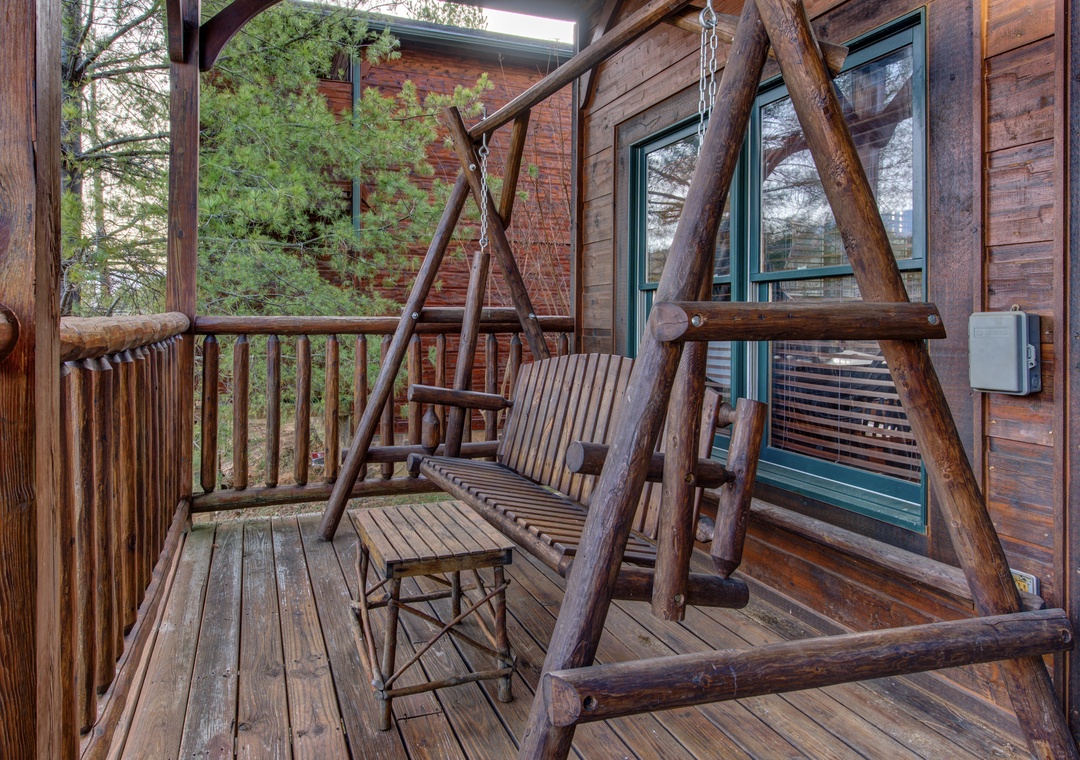 Settle into your private porch swing surrounded by lush forest views. The handcrafted wooden swing and nearby table create the perfect spot to sip morning coffee or unwind after a day exploring the area.