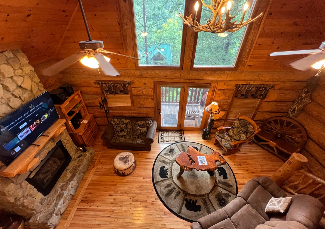 A stunning birds-eye view of your cozy mountain retreat, where rustic wood beams and a stone fireplace create the perfect gathering space to unwind after your adventures.