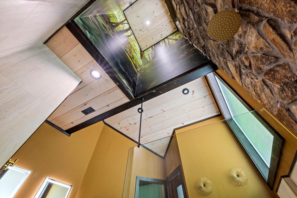 Look up and marvel at soaring ceilings with skylights framing the forest canopy. Modern design meets natural stone and timber, creating an airy retreat that blurs indoor-outdoor living.