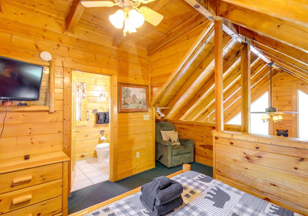 Your cozy loft bedroom features rustic wood walls, comfortable seating, and an ensuite bathroom for ultimate privacy and convenience.