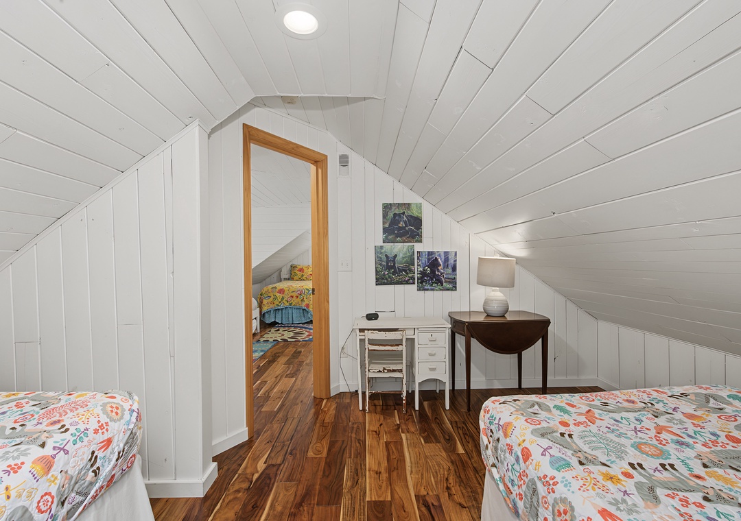Step into your bright and cozy sleeping space with charming sloped ceilings and warm hardwood underfoot. The cheerful bedding and thoughtful workspace make this your perfect retreat after a day of adventure.
